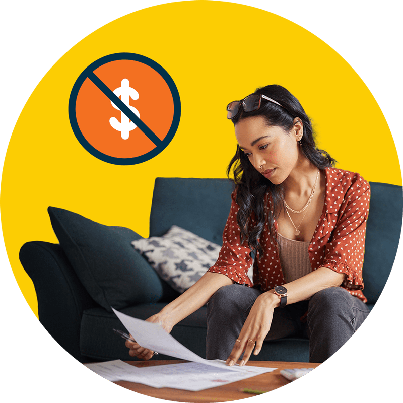 A young woman reviews loan documents while sitting on a couch.