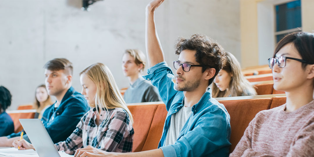 A male college student raises his hand in class.